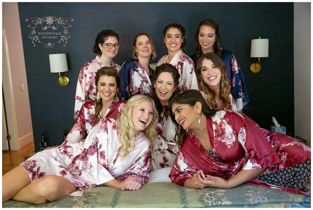 bride and her bridal party laugh on bed