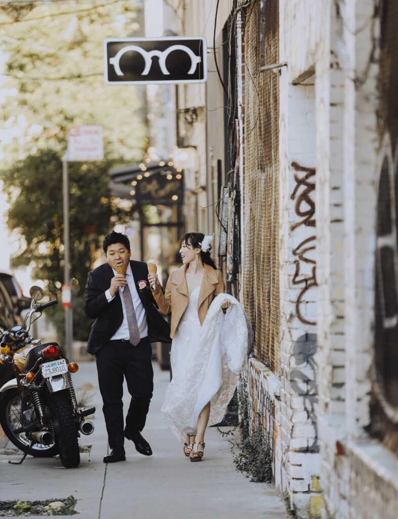Modern wedding couple walk through urban city streets with ice cream