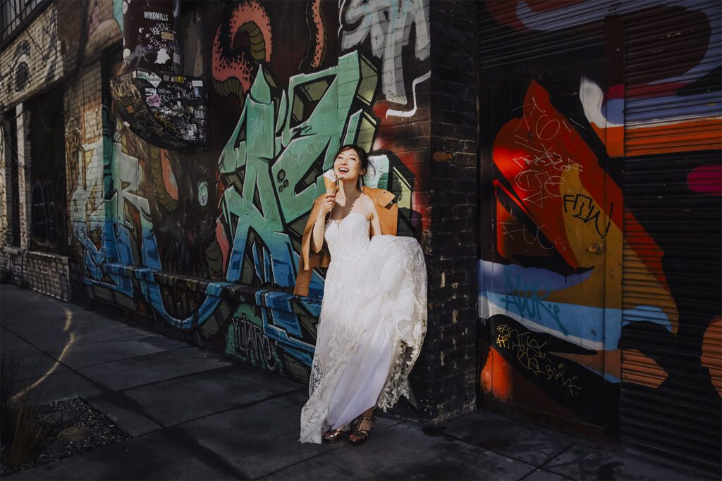 Bride eats ice cream in front of grafitti city walls