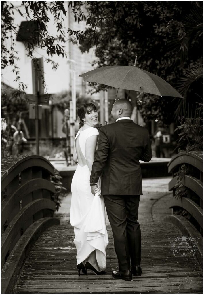 Wedding portrait of couple on bridge in Sonoma with umbrella in the rain