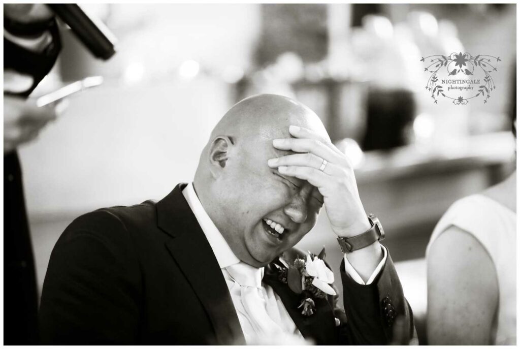 Groom laughs at the speeches during his wedding reception