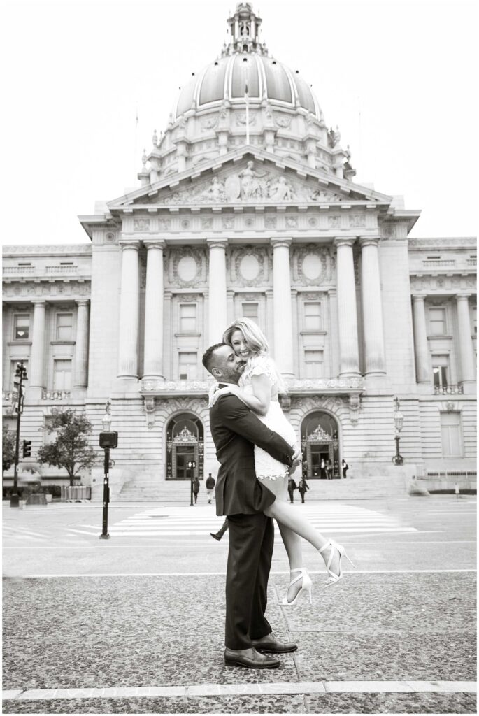 Cute San Francisco City Hall wedding photo of groom picking up bride on the street