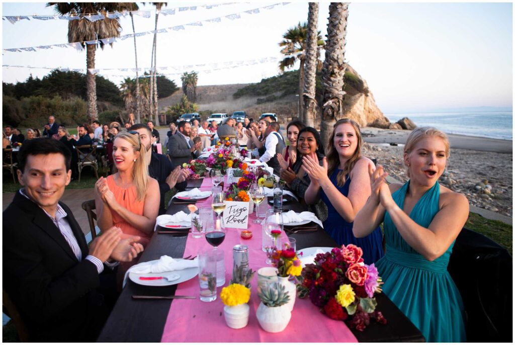 guests clap for wedding couple as they enter their reception on beach in santa barbara