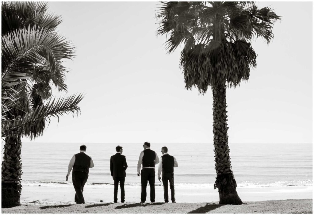 black and white photo of groomsmen on beach with palm trees at santa barbara beach wedding