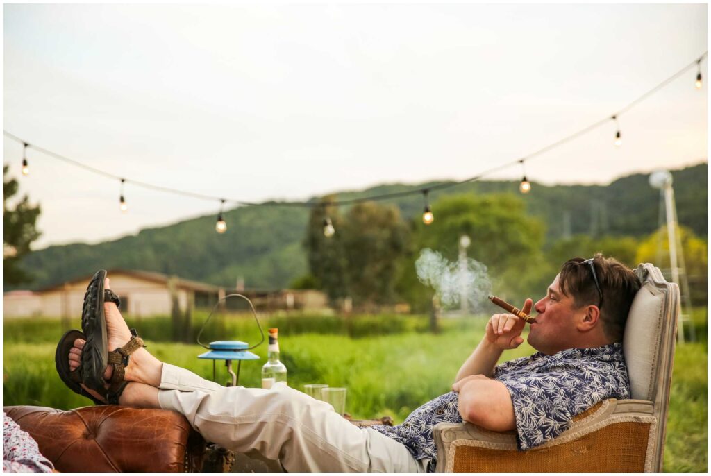 wedding guest smokes cigar in backyard at this intimate rustic wedding