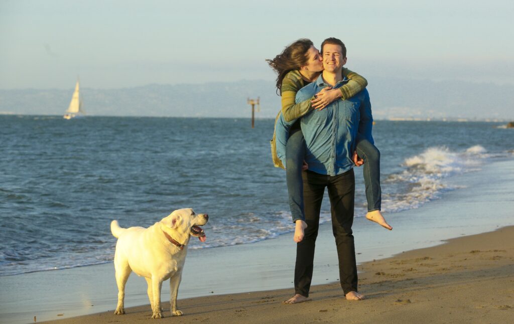 laughing couple on beach with golden gate bridge by Nightingale Photography